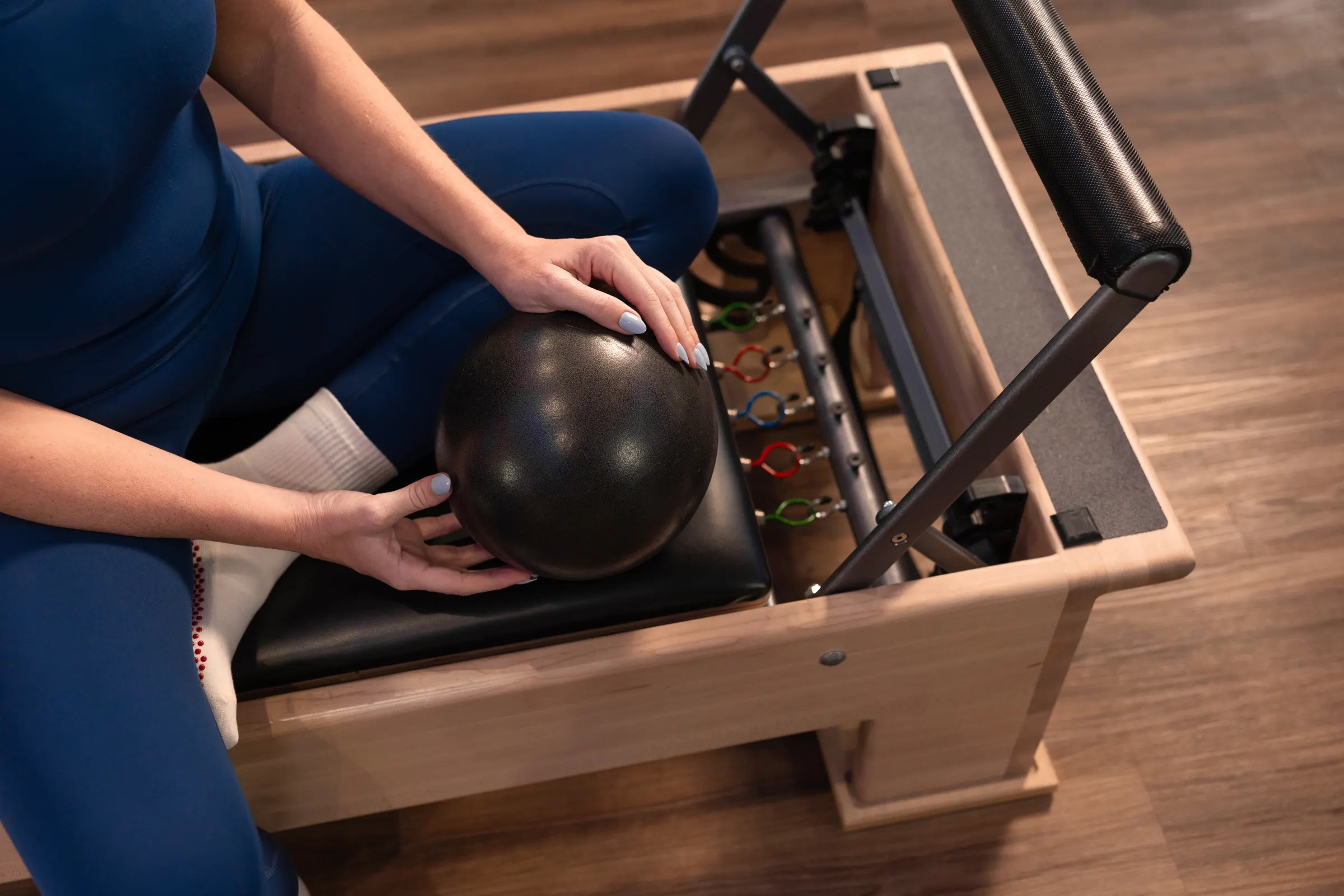 Member holding a Pilates ball on the Reformer
