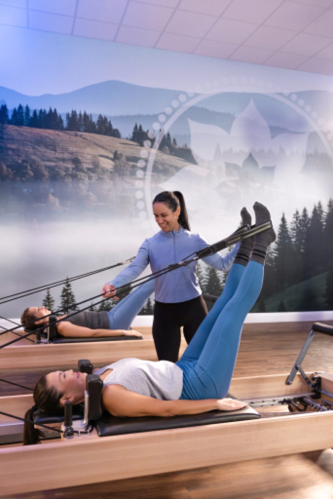 Instructor guiding a member through an Intro Class on the Reformer